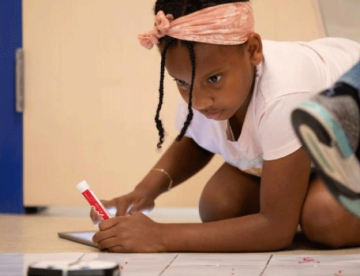 An image of a girl in school with a marker in her hand