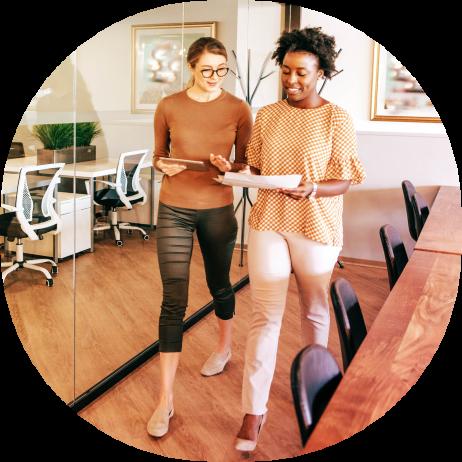 Two female employees walking and having a conversation in a conference room