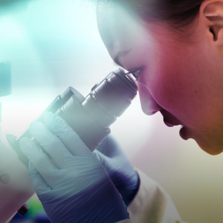 Female scientist looking into a microscope in a lab