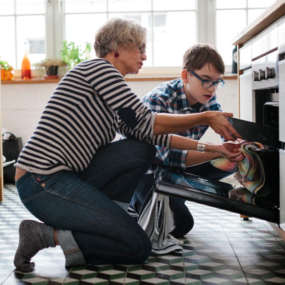 A grandmother and grandson take a pan out of the oven together