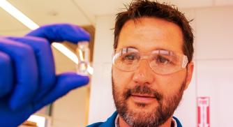 male scientist holding small test tube