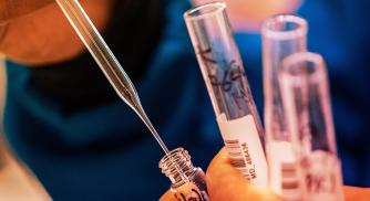 Close up of a pipette being inserted into a vial