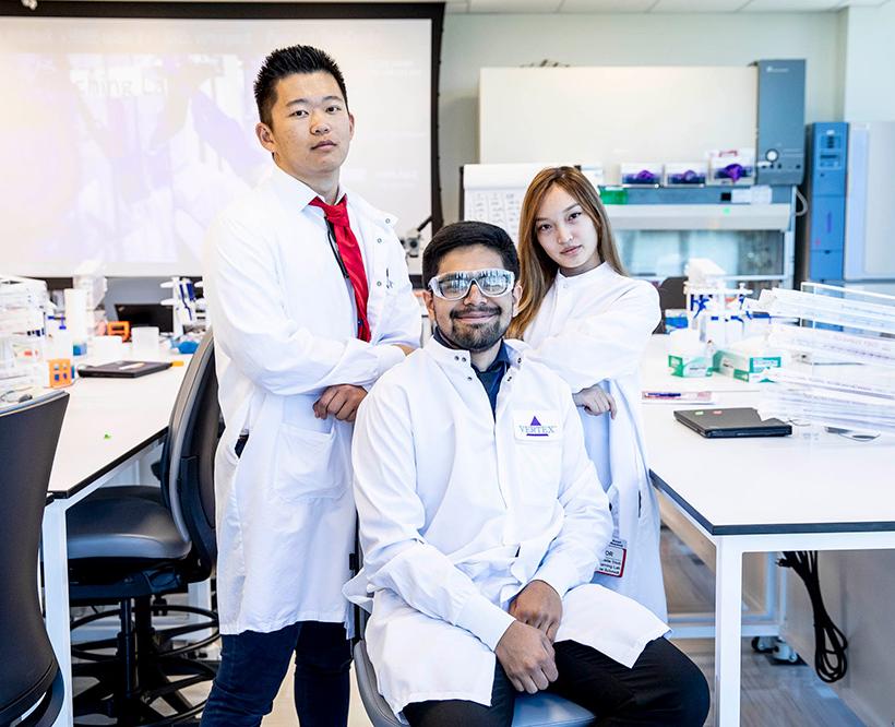 3 STEAM Students posing in Vertex lab coats in the Learning Labs