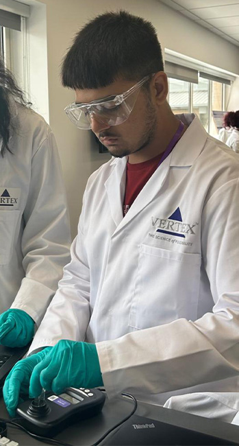 An image of Amaan Butt wearing a white Vertex lab coat and using lab equipment at the Oxford Learning Lab.