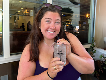 An image of Makenzie Quick holding an iced drink smiling at the camera.