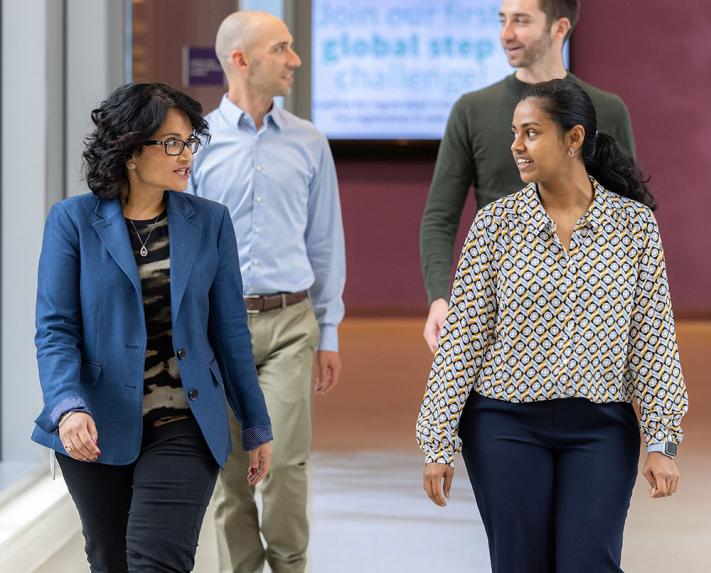 4 Vertex employees walking down a hall and talking to one another