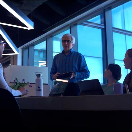 An image of coworkers holding a meeting around a long table with a Vertex water bottle resting on the table