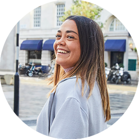 An image of Gaia, a patient living with beta thalassemia, smiling while walking across a city street