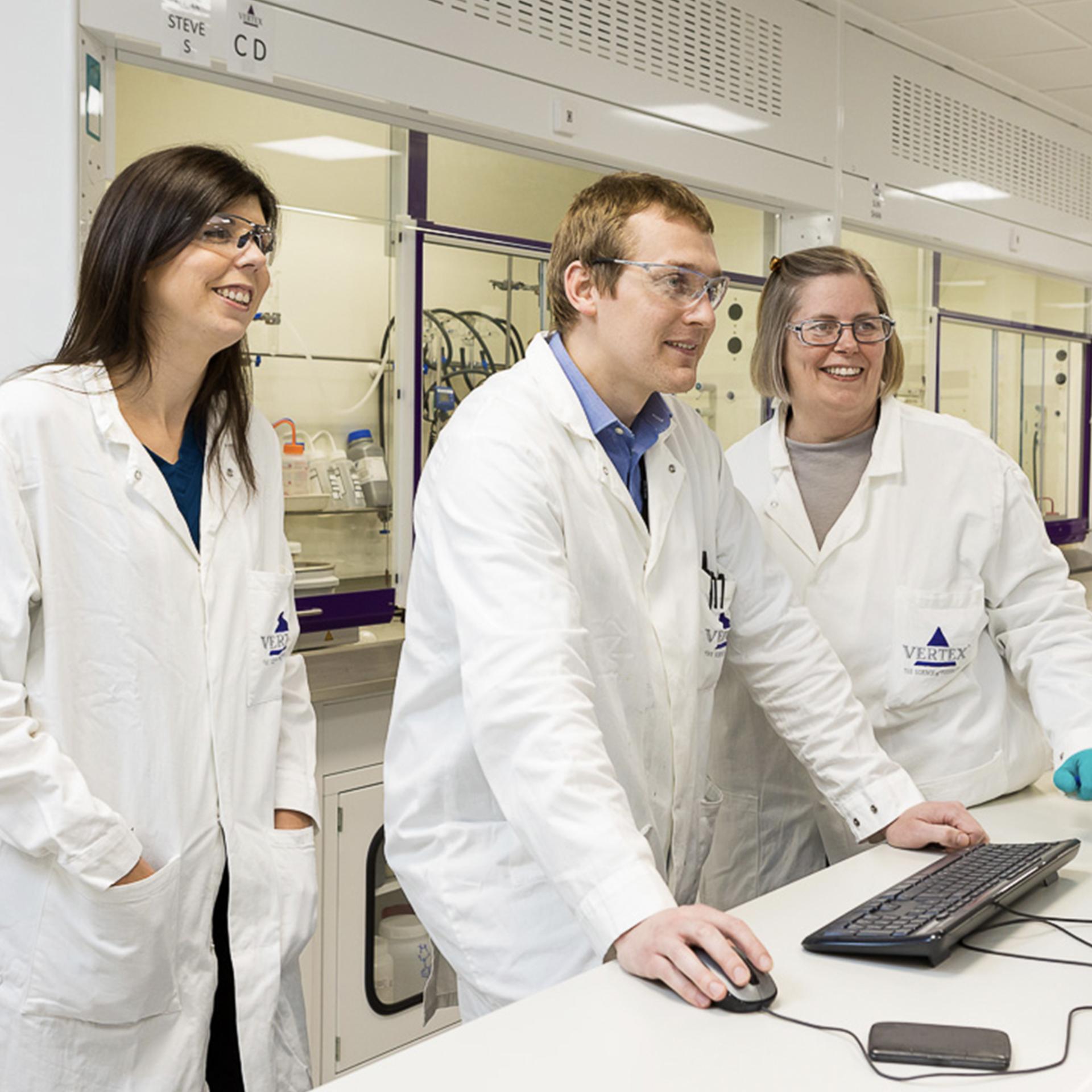 3 Vertex scientists together in the lab looking at a computer