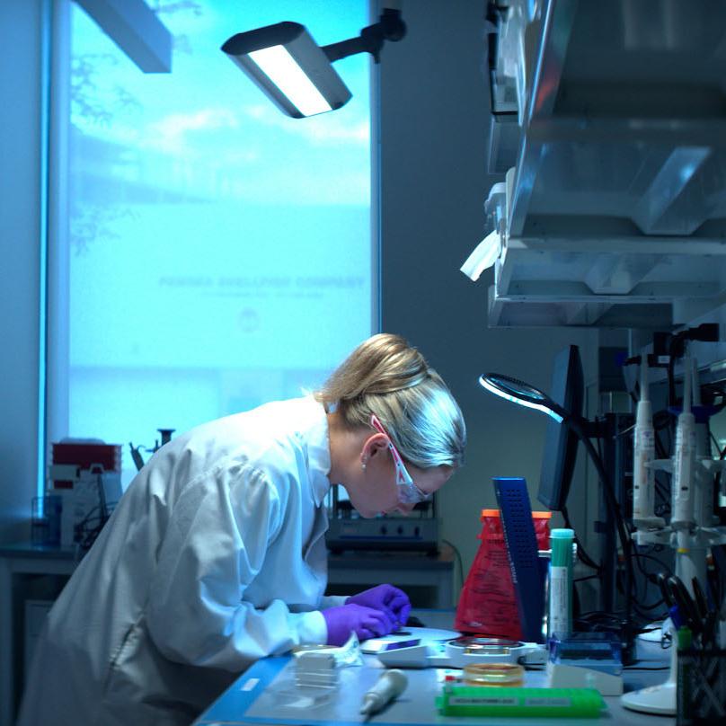 An image of a Vertex scientist wearing a white lab coat carefully using lab equipment